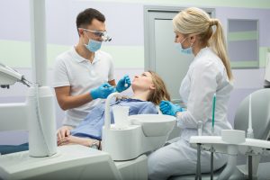 Girl patient in the dental clinic. Teeth whitening UV lamp with photopolymer composition.