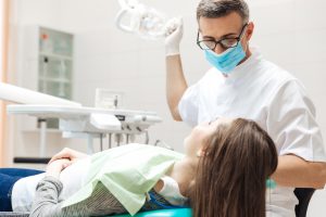 Dentist very carefully check up and repair tooth of his young female patient in the clinic