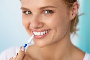 Healthy White Teeth. Closeup Portrait Of Beautiful Happy Smiling Woman With Perfect White Smile Holding Teeth Whitening Pen. Dental Beauty And Health, Tooth Care Concept. High Resolution Image